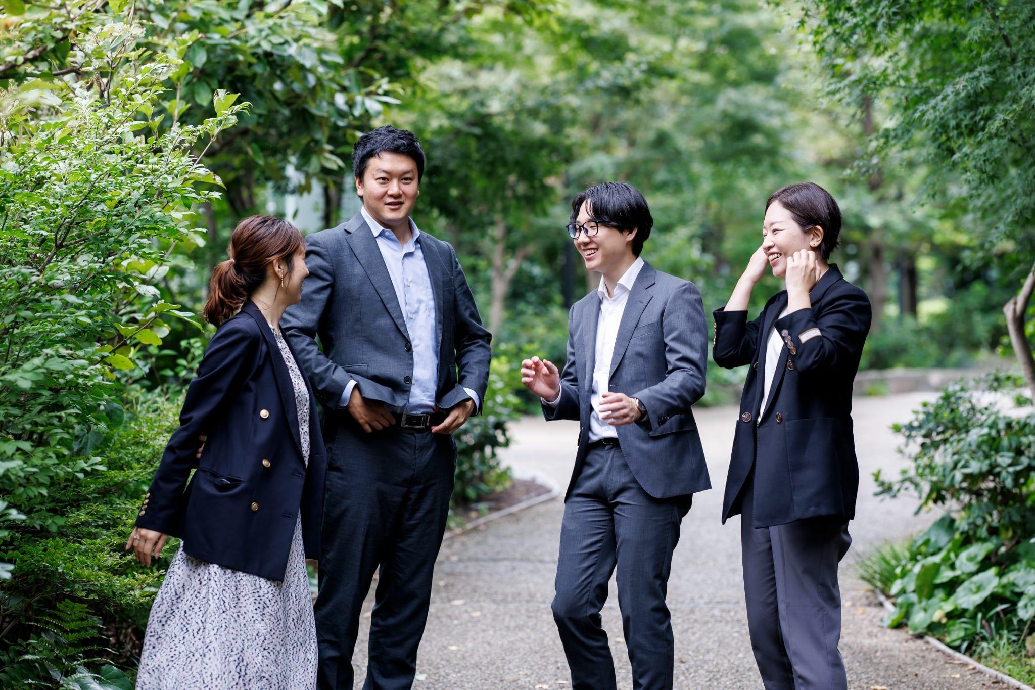 木々に囲まれた屋外で会話するKUMU Worksのメンバー